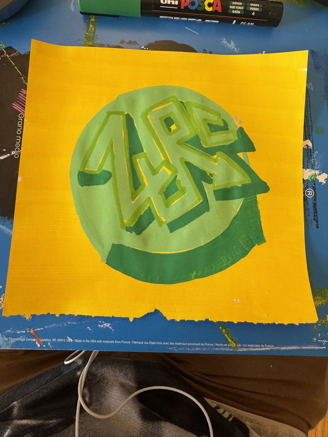 ZURC letters sketched in light green inside a green disc on a yellow sheet, unfinished